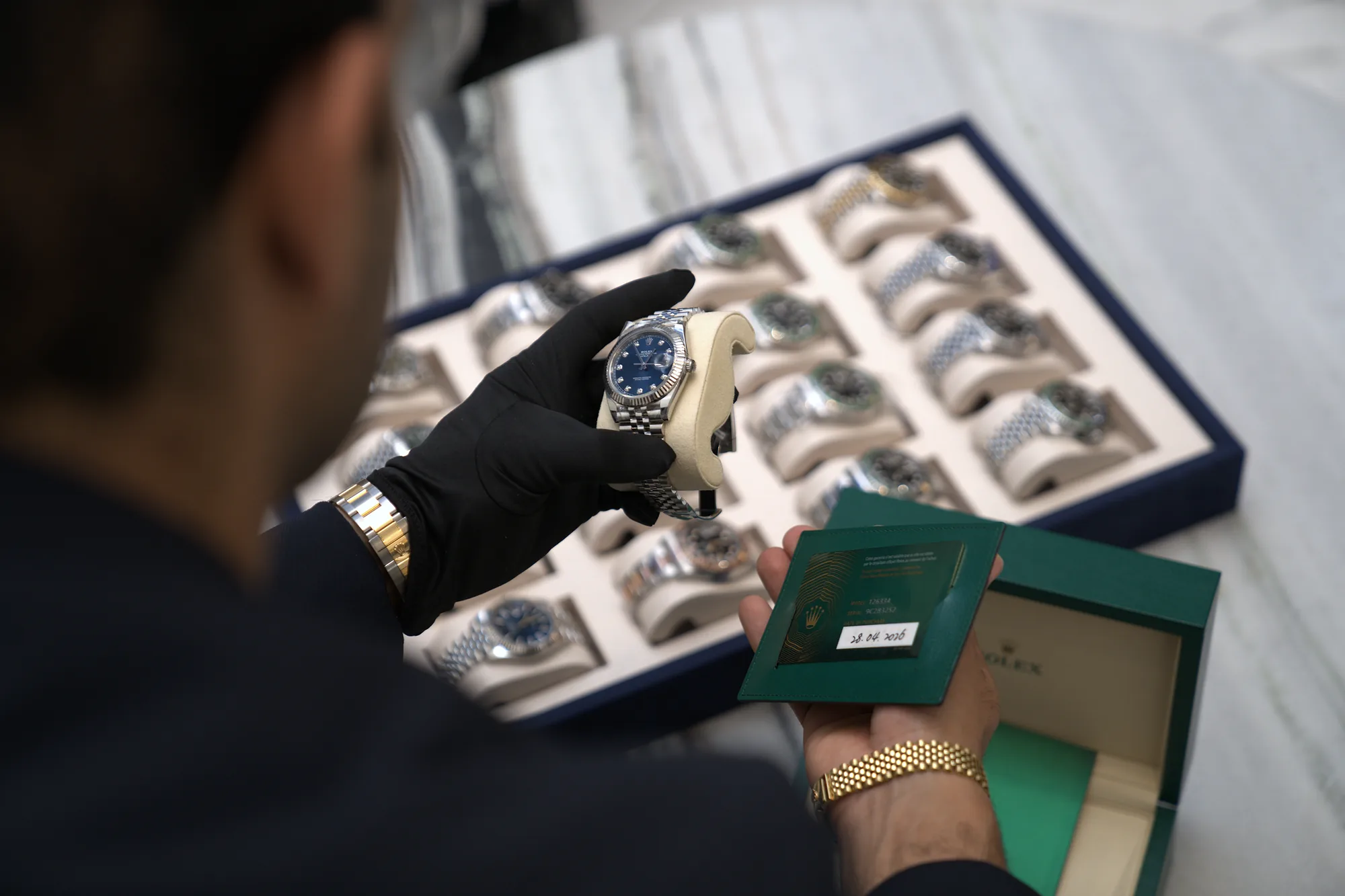 A gloved SASO specialist authenticating a Rolex against its papers