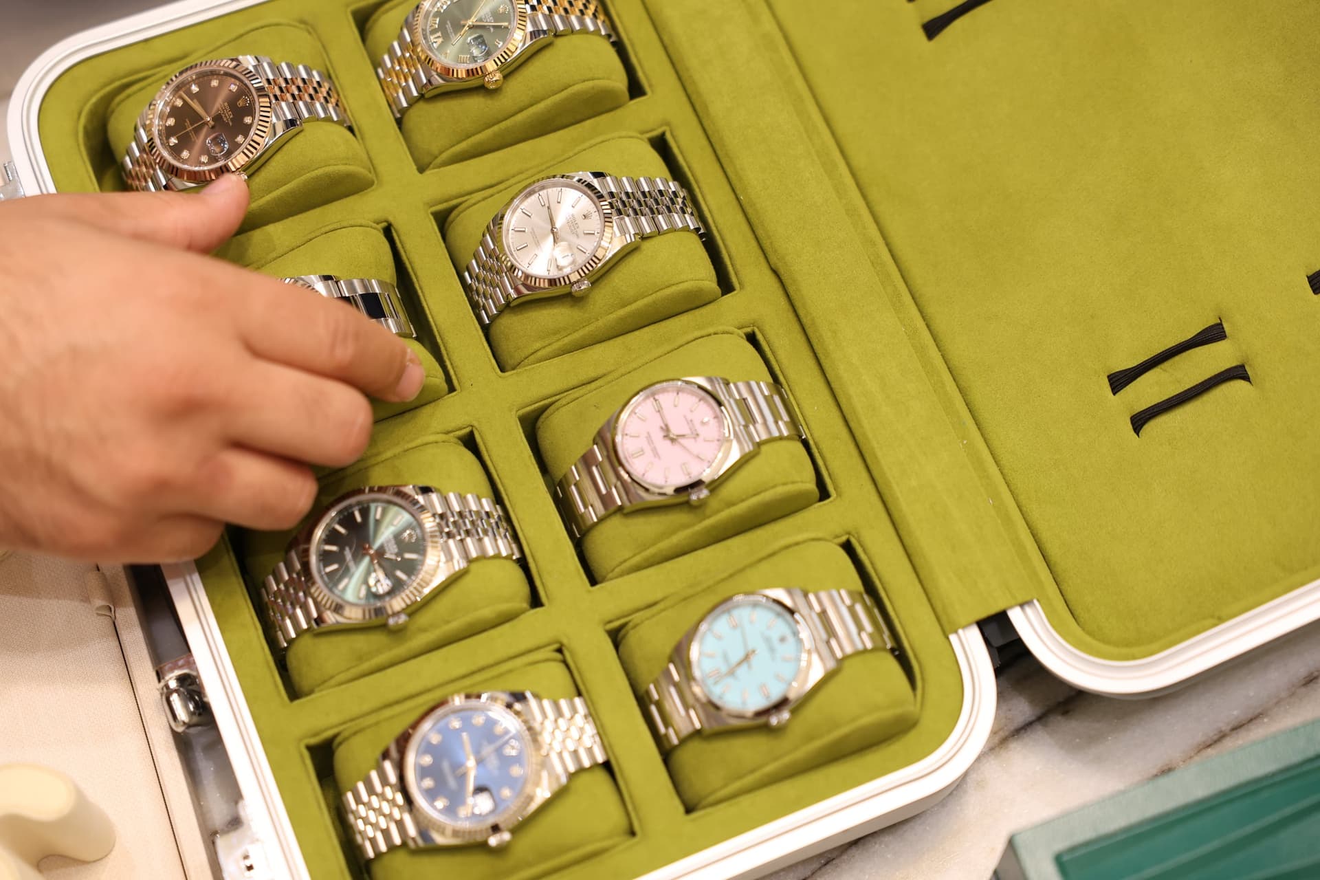 A hand holding a roll of Rolex watches