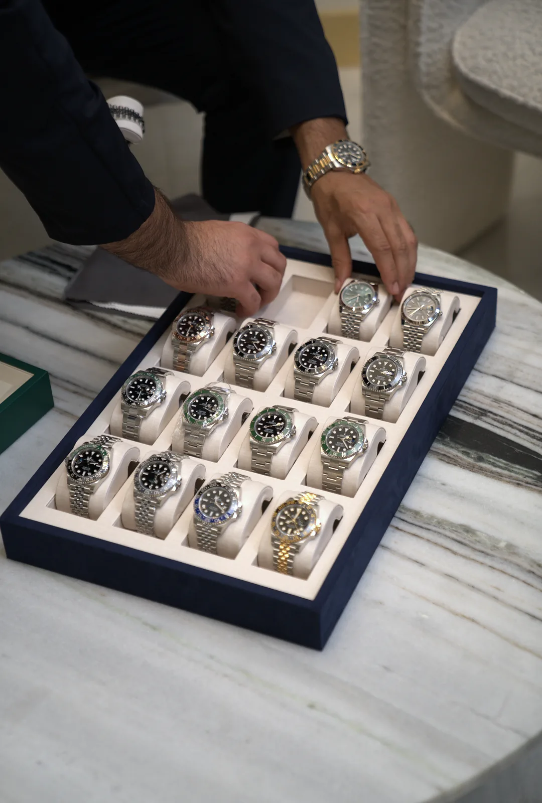 A hand lifting a Rolex from the tray