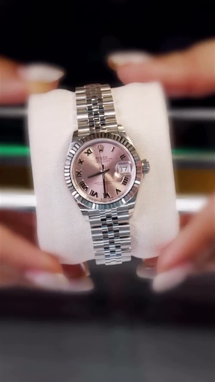 A Rolex Datejust with a pink dial, held in hand